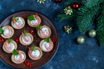 Tartlets with cream cheese and shrimp. Decorated with sprigs of dill and parsley. Seafood.