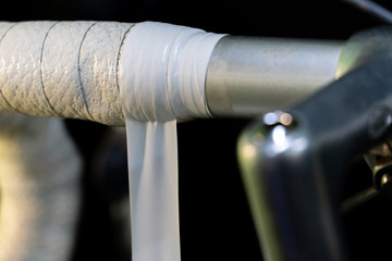 Road bike handlebars and dual control lever on a black background. Install handlebar tape white. Bicycle repair in a modern workshop. White insulating tape close-up.