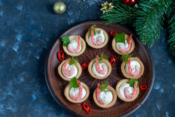 Tartlets with cream cheese and shrimp. Decorated with sprigs of dill and parsley. Seafood.