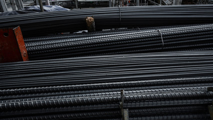 Building armature in the warehouse of metallurgical products or on construction site. Stack of heavy metal reinforcement bars with periodic profile texture. Steel construction armature.