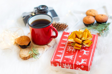 New Year and Christmas, cozy concept, coffee with cupcakes, on a fluffy plaid with a fir branch, a retro camera, and a Christmas present