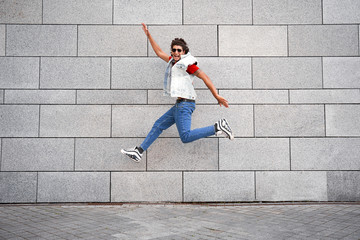 Young adult man jumping against city wall