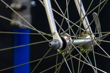 Bicycle repair. The front wheel is on a stand on a black background. Rim and spokes close-up. Mechanic levels the wheel in the workshop.