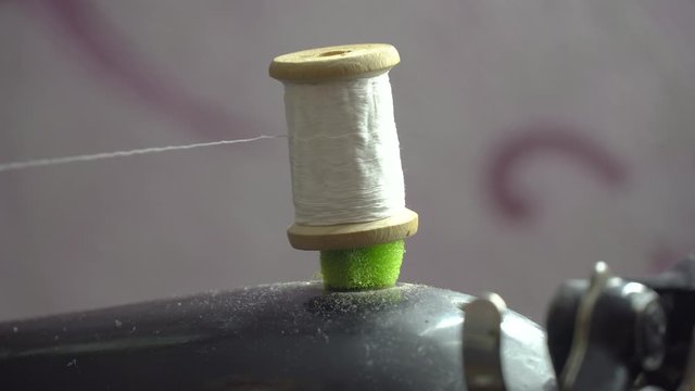 Thread is Wound on a Robbin. Close-up of a Spool with Thin Thread on Working a Vintage Sewing Machine. Spool with thin white thread on working a sewing machine. Sewing bobbin being wound up on a