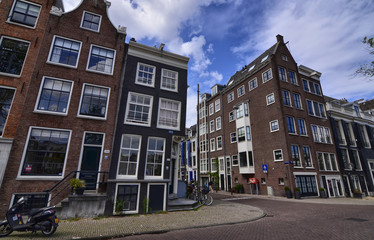 Obraz premium Amsterdam, Holland, August 2019. The typical houses of the historic center: made of brick and with white window frames. People walk in the street.