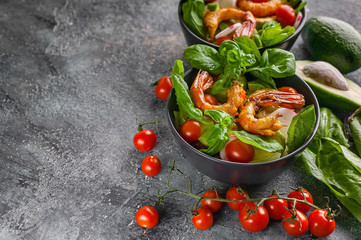 Seafood salad with shrimp, avocado, lettuce in a bowl on a dark background. Horizontal shot. Copy space