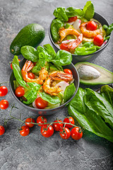 Close-up tasty seafood salad. Shrimp, avocado, lettuce in a bowl on a dark background. Vertical shot