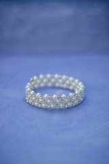 Women's jewelry bracelet in white pearls beads for bride close up on blue background