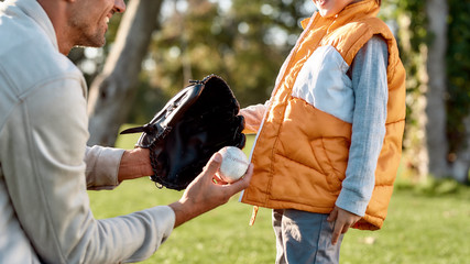 Support your child. Father teaching son baseball in the park on a sunny day