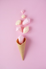 Hand holds a waffle cone with paper diamonds on pink background. Holiday concept.