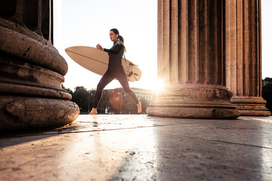 Young woman with surfboard on the way to Eisbach, Munich, Germany