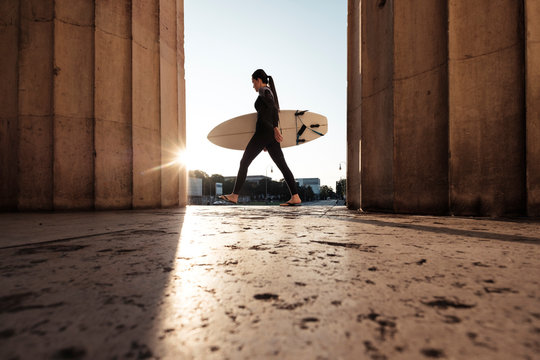 Young woman with surfboard on the way to Eisbach, Munich, Germany