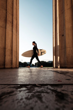 Young woman with surfboard on the way to Eisbach, Munich, Germany
