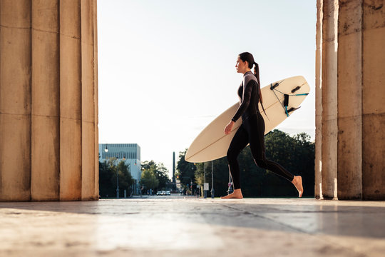 Young woman with surfboard on the way to Eisbach, Munich, Germany