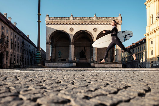 Young woman with surfboard on the way to Eisbach, Munich, Germany
