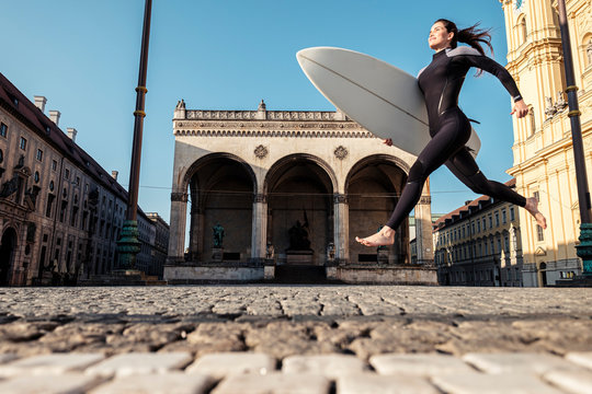 Young woman with surfboard on the way to Eisbach, Munich, Germany