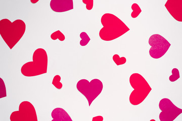 Red and pink hearts are scattered in a chaotic order on a white background. Valentine's day holiday card