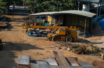 Automobile crane with risen telescopic boom outdoors. Mobile construction crane on a constructin site. Crane machine stand by waiting for work under the construction building. Heavy industry.