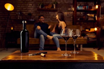 Glasses of red wine on table at home with couple