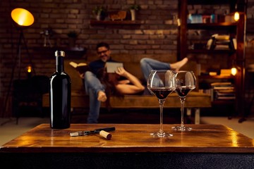 Glasses of red wine on table at home with couple