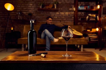 Glass of red wine on table at home man sitting