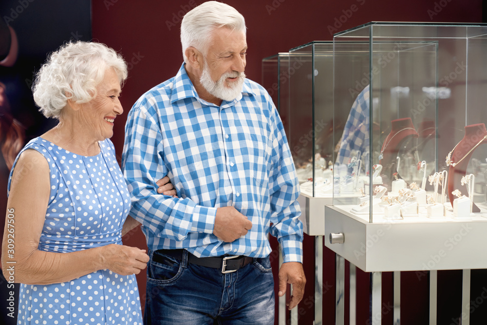 Wall mural happy aged couple choosing jewelry in shopping mall