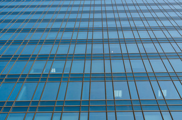 Reflection of the sky in the windows of a building. Perspective and underdite angle view to modern glass building skyscrapers over blue sky. Windows of Bussiness office or corporate building.