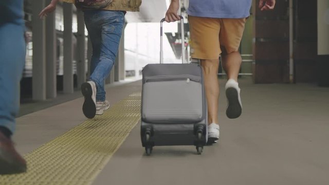 Back view of four passengers chasing train.