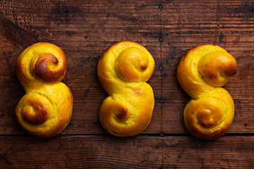 Swedish traditional christmas bun Lussekatter or Lussebullar on a rustic wooden table background