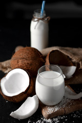 fresh coconut milk in a glass against a dark background, coconut cosmetic cream, milkshake with coconut slices