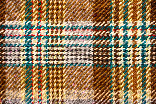 Brown checkered fabric with colored threads. Scottish wool. Fabric for plaid coat and suit. Close-up. Background