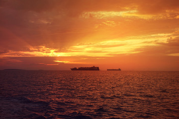 Romantic sunset over the Aegean sea with beautiful golden colours and clouds as seen from cruising yacht in Cyclades isalands, Greece