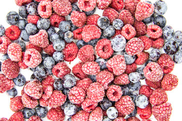 A Berry mix from frozen raspberries and blueberries. A Frozen Berries from freezer.  A sweet background with frozen raspberries and blueberries.   A heathy Berries in the background.