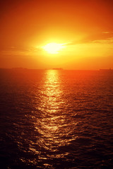 Romantic sunset over the Aegean sea with beautiful golden colours and clouds as seen from cruising yacht in Cyclades isalands, Greece