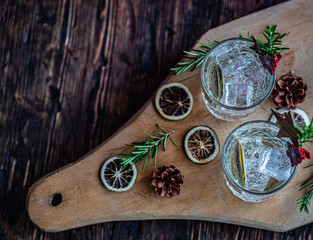 Ideas of winter drinks from gin and tonic for the new year. A bottle of gin and water tonic on a wooden table