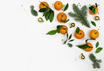 Minimal flat lay Christmas composition of fir tree branch, tangerine and gold balls on white