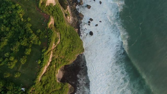 Landscape from Pura Uluwatu cliff. Waves break on rocky shore. Seascape, rocks, ocean.