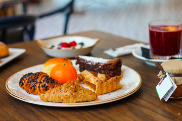 detail of breakfast table with chocolate cakes, jam, red orange juice, mandarin, croissants, butter, yogurt with raspberries and blueberries - 309275321