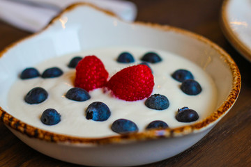 detail of ceramic bowl with yogurt with raspberries and blueberries