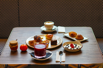 breakfast table with chocolate cakes, jam, red orange juice, mandarin, croissants, butter, cappuccino, sfogliatella, yogurt with raspberries and blueberries - 309275361