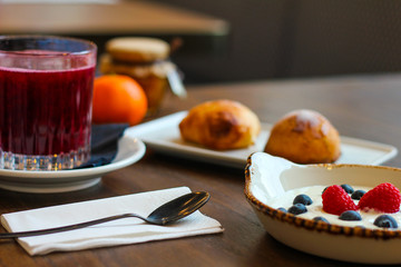 detail of breakfast table with chocolate cakes, jam, red orange juice, mandarin, sfogliatella, spoon, yogurt with raspberries and blueberries - 309275381