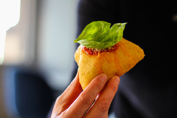 hand holding a montanara, tipical street food fried with tomato, mozzarella, basil and parmesan cheese from naples, italy - 309275518