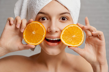 Girl in towel looking at camera while keeping fresh fruits
