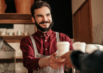 Friendly waiter selling coffee to faceless client