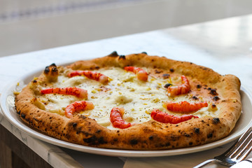 pizza with shrimps, lemon flakes and pepper in a typical Italian pizzeria