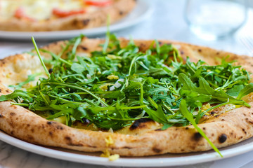 pizza with rocket salad, lemon flakes, mozzarella in a typical Italian pizzeria