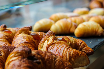 rows of freshly baked crunchy croissants with chocolate and jam and some sfogliatelle in the background - 309277520