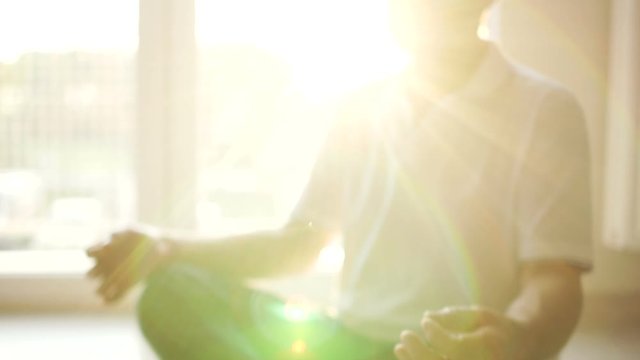 Meditation and yoga. Spiritual practice, an elderly yogi sits on the floor in a lotus position. Sun glare