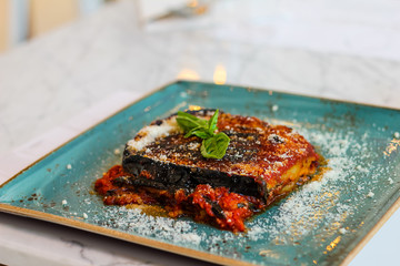 eggplant parmigiana with parmesan cheese, fresh basil and tomato in Italian restaurant
