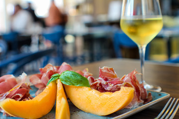 fresh summer aperitif with melon, casertano black pig ham and a glass of white wine